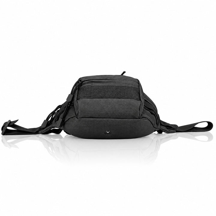Black tactical waist pack resting on its base, showing the lower front pouch, zipper pulls, side straps, and reinforced bottom construction.