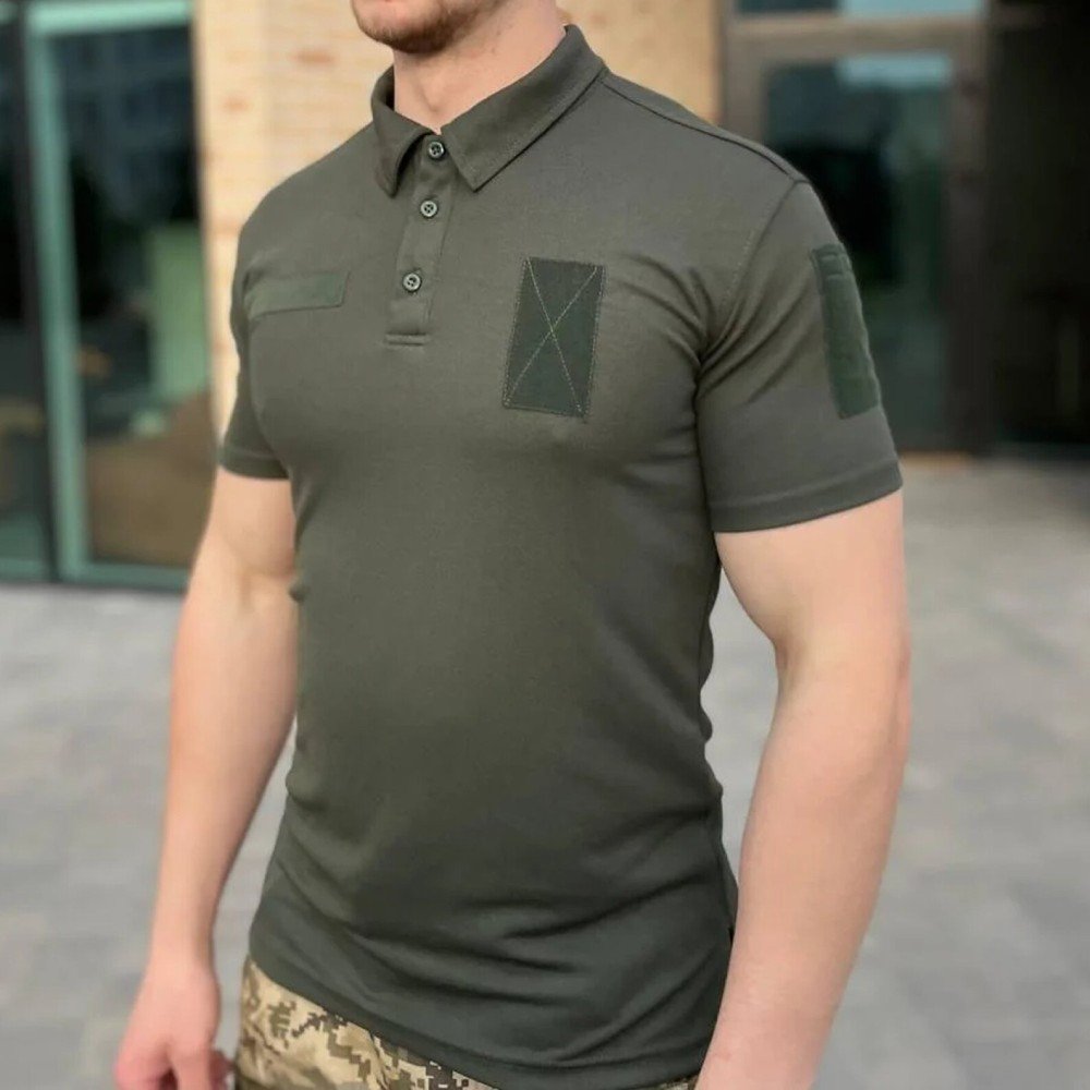 Close-up front view of a man wearing an olive tactical polo shirt with velcro patches and a chest pocket.