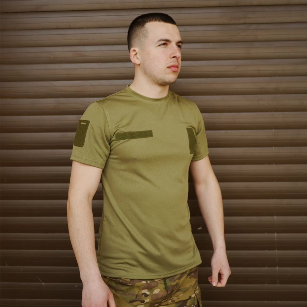 Side view of a man wearing an olive green t-shirt with detailed sleeve patches.