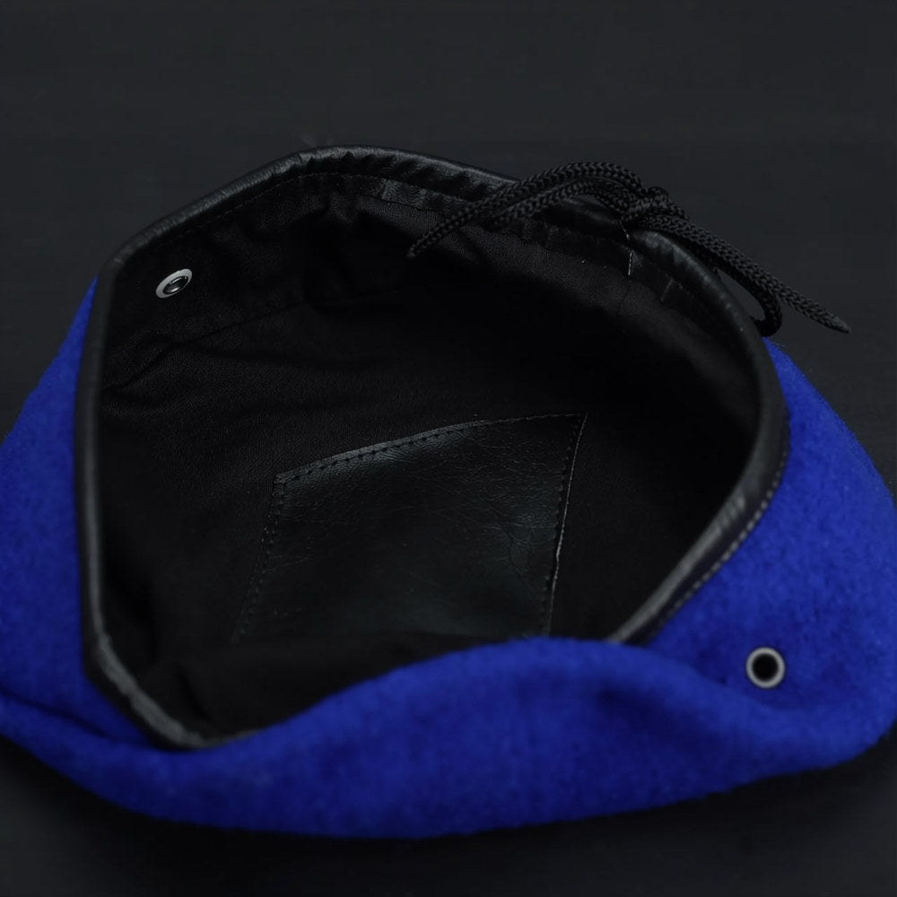 Inside view of blue military wool beret showing black lining, drawstring, and leather sweatband