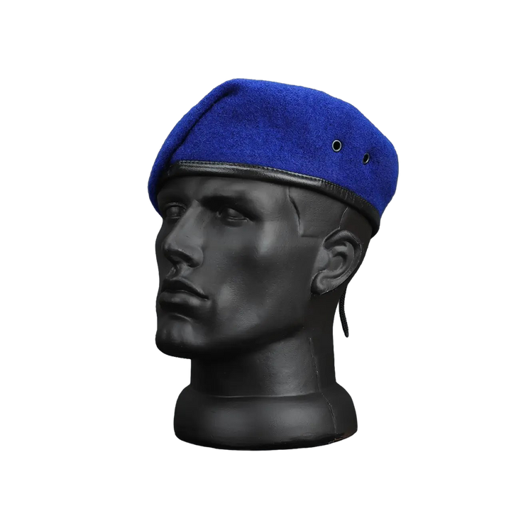 A royal blue wool beret with a black leather trim and chin strap, displayed on a black mannequin head against a white background.