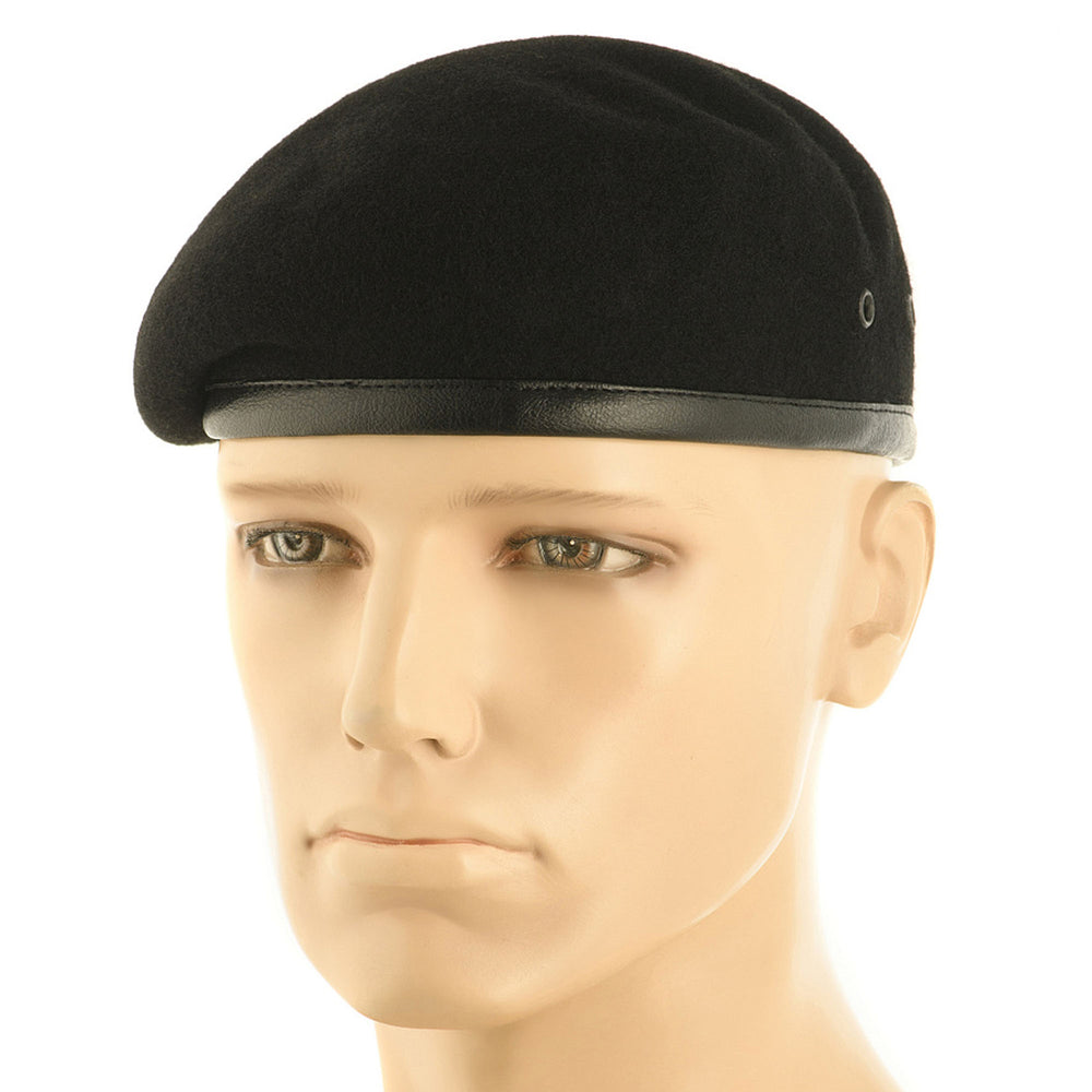 Black beret hat made from natural wool, worn on a mannequin head, with a black leather band around the lower edge and classic military round shape.