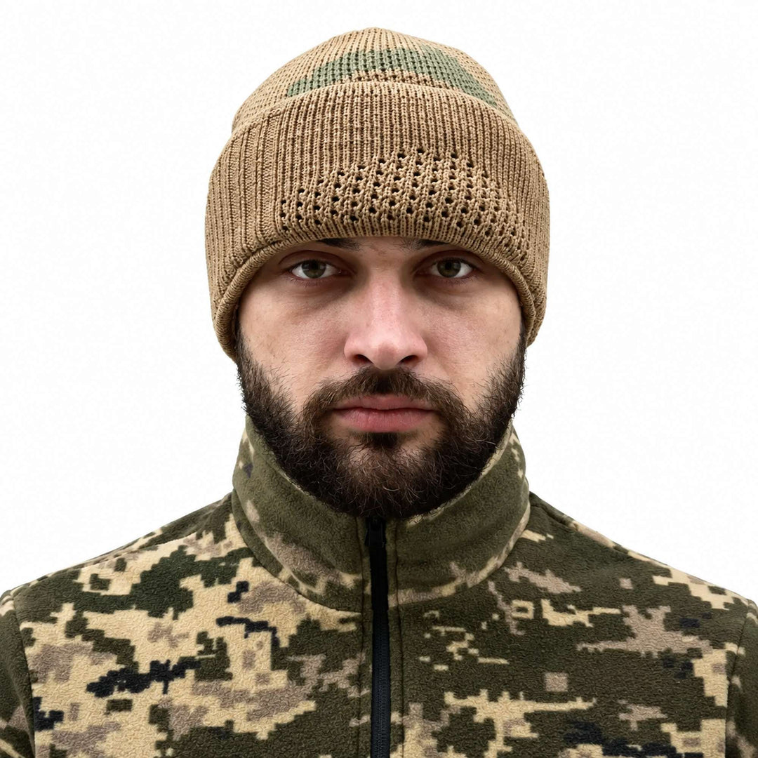 Khaki knitted wool balaclava worn as a winter beanie with the face section folded up, showing the ribbed knit cuff and subtle green camouflage pattern on the crown.