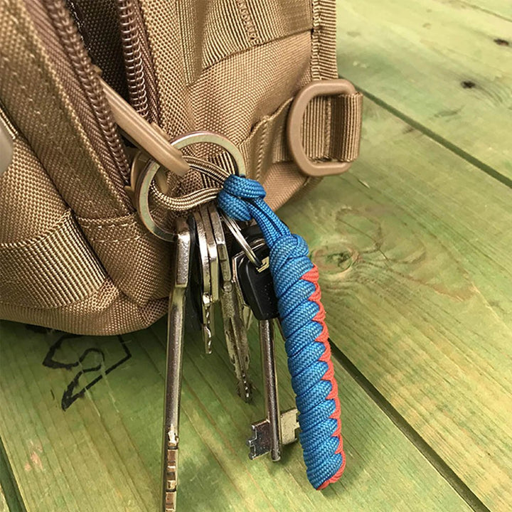 Detail of a tactical chest bag with keyring and paracord lanyard on coyote fabric.