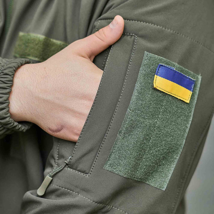 Zippered arm pocket on a tactical military jacket with Velcro patch and Ukrainian flag.