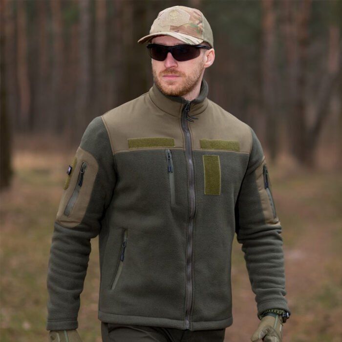 Front view of a khaki tactical fleece jacket worn by a man in a forest.