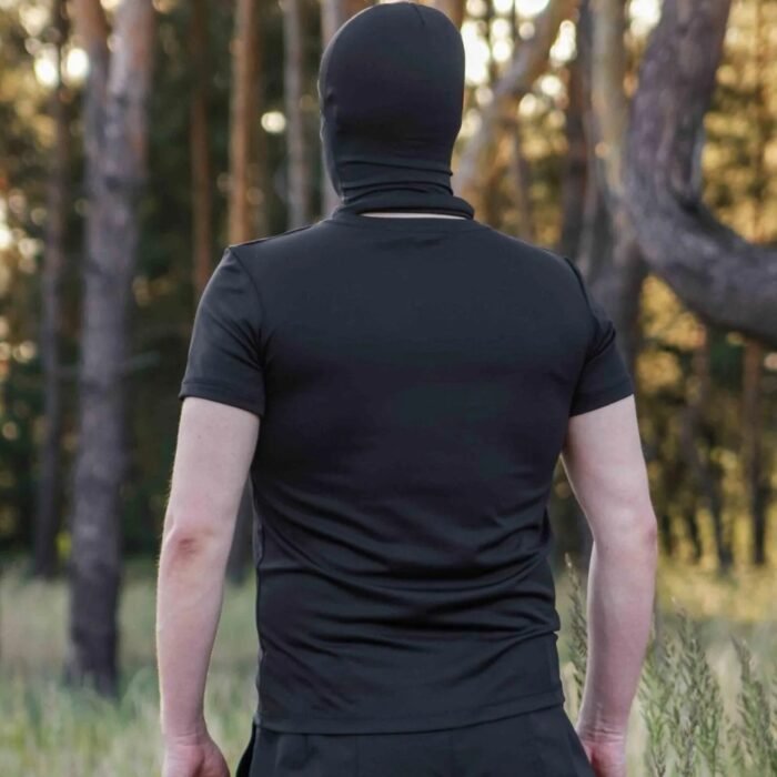 Rear view of a man wearing a black t-shirt and matching face cover in a forest.