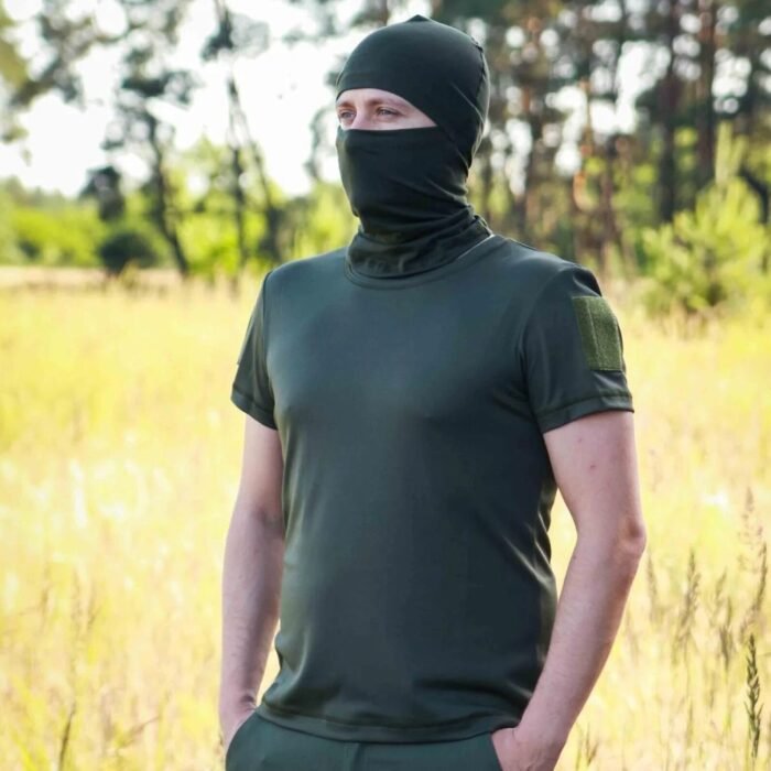Front view of a man wearing a dark green t-shirt and face cover in the woods.