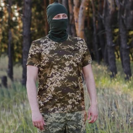 Front view of a man wearing a pixel-pattern camouflage t-shirt and a matching face cover in the woods.