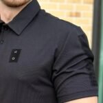 Close-up of a black tactical polo shirt focusing on the shoulder and upper sleeve.
