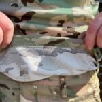 Close-up of the lower half of a multicam-patterned t-shirt tucked into camouflaged pants.