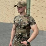 Full view of a man standing in a multicam camouflage t-shirt.