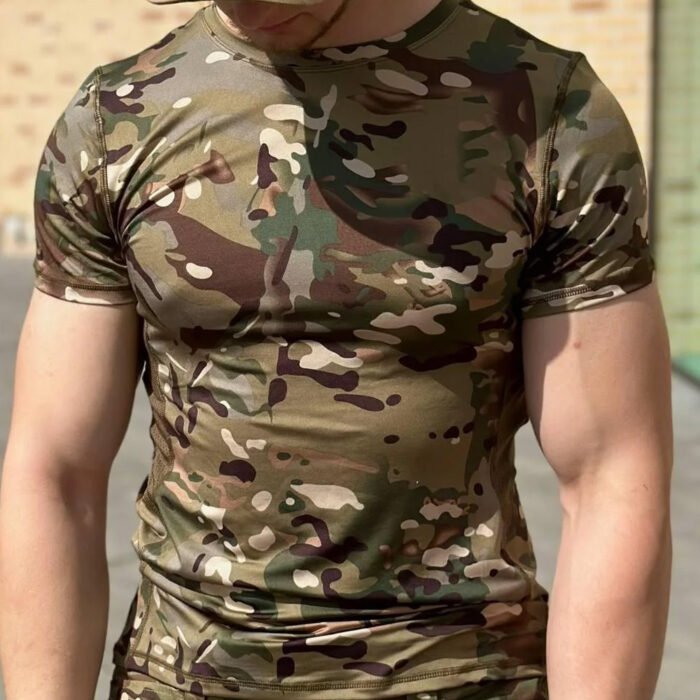 Full view of a man in a multicam camouflage t-shirt standing confidently outdoors.