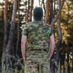 Man seen from behind wearing a multicam t-shirt in a natural setting.
