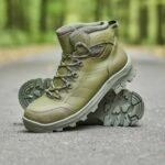 A single olive combat boot stacked on another, highlighting its thick, deep-treaded sole designed for superior grip.