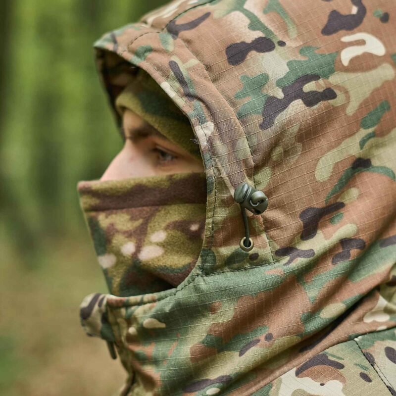 Side view of a multicam jacket with an adjustable hood, designed for wind and cold protection.