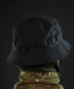 Soldier wearing black tactical sun hat during outdoor operation, side view